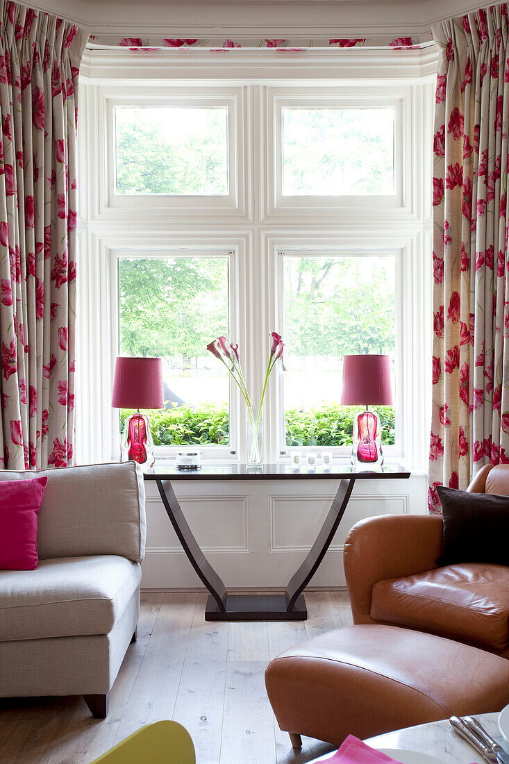 Matching lamps on side table in window of contemporary London home, UK