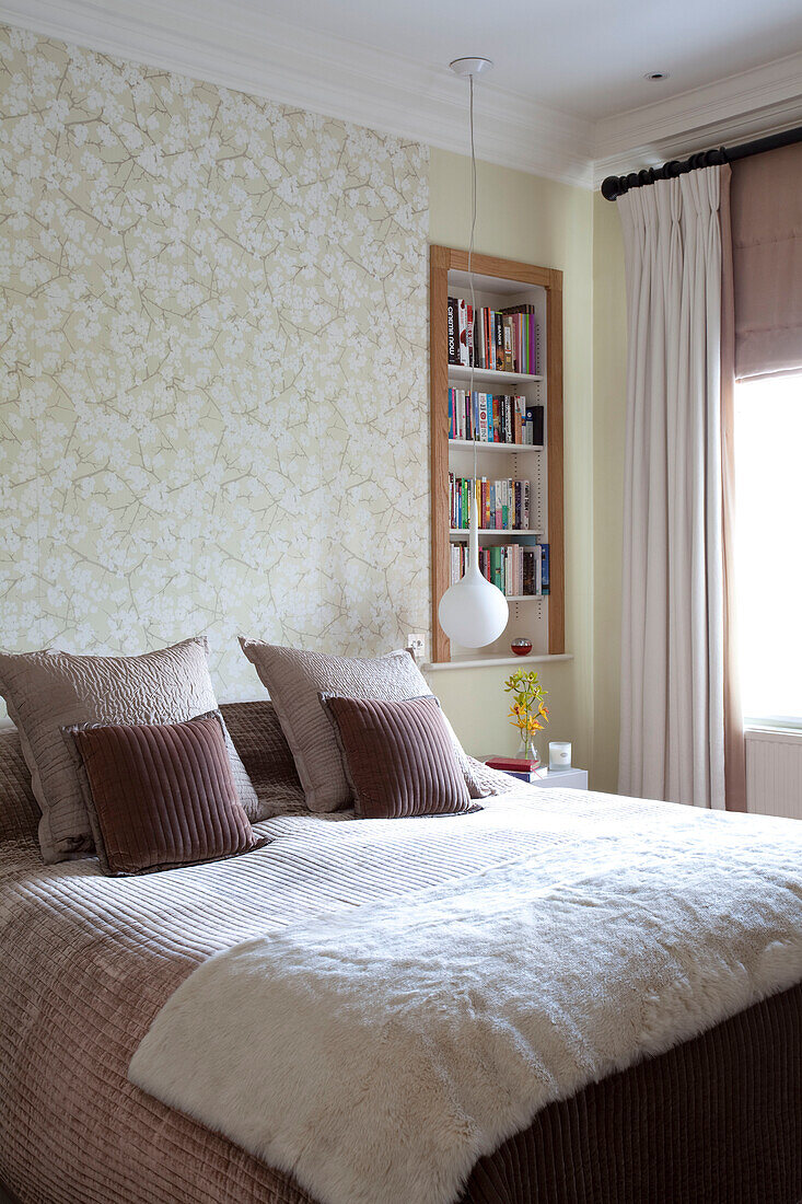 Cream fur throw on bed in room with recessed book shelving, contemporary London home, UK