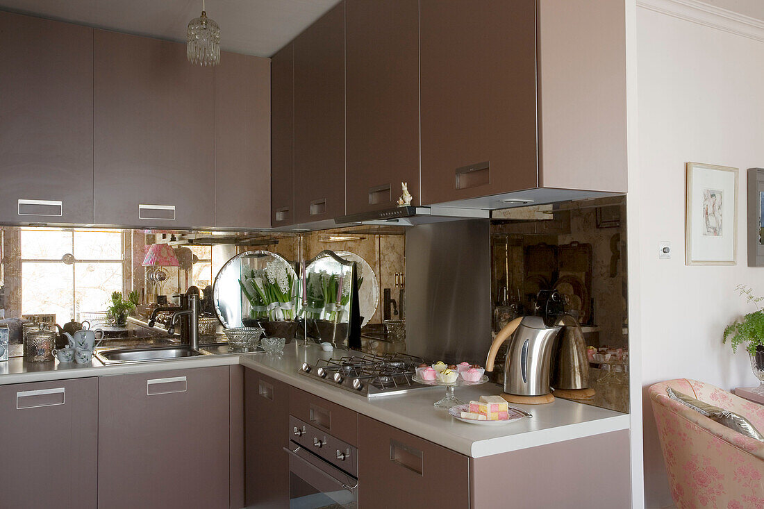 Brown fitted retro fitted kitchen in open plan apartment with mirrored splashback