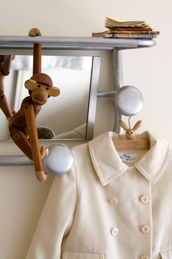 Wooden monkey and coat hang on silver shelf rack in London home UK
