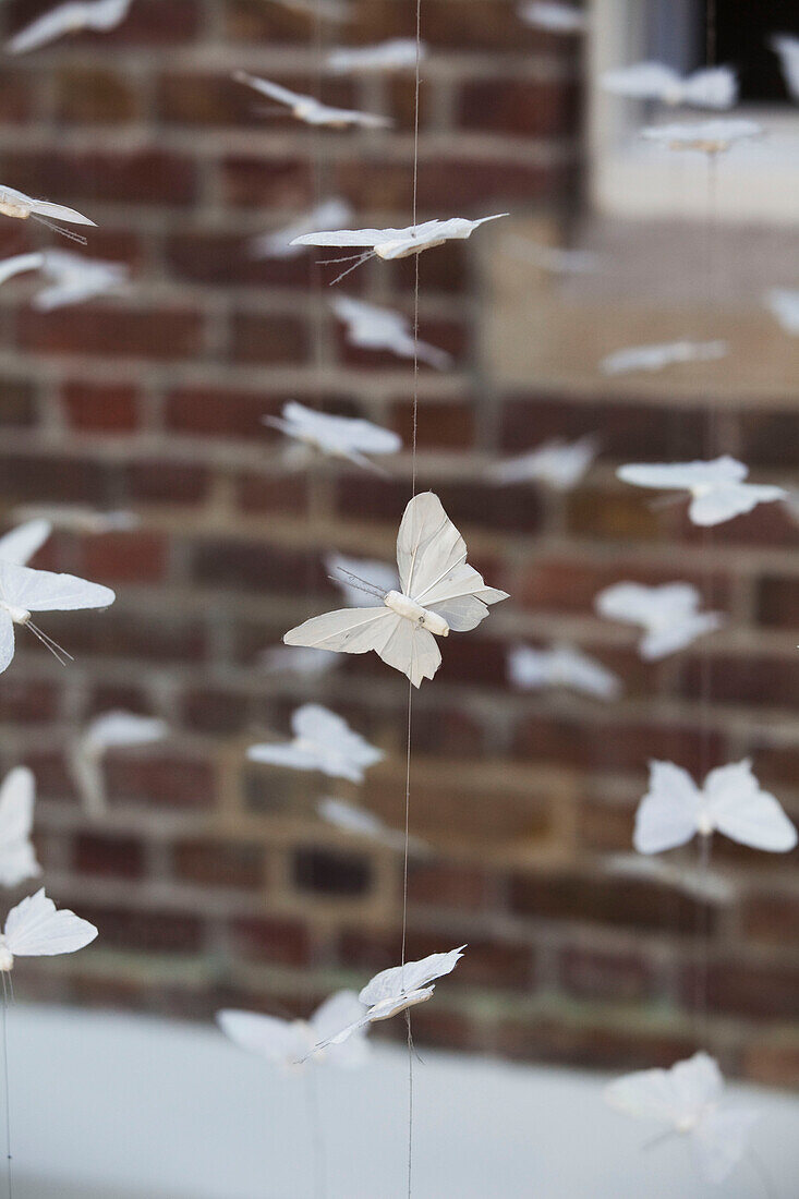Schmetterlingsmobile und freiliegende Ziegelwand in einem modernen Londoner Stadthaus, UK