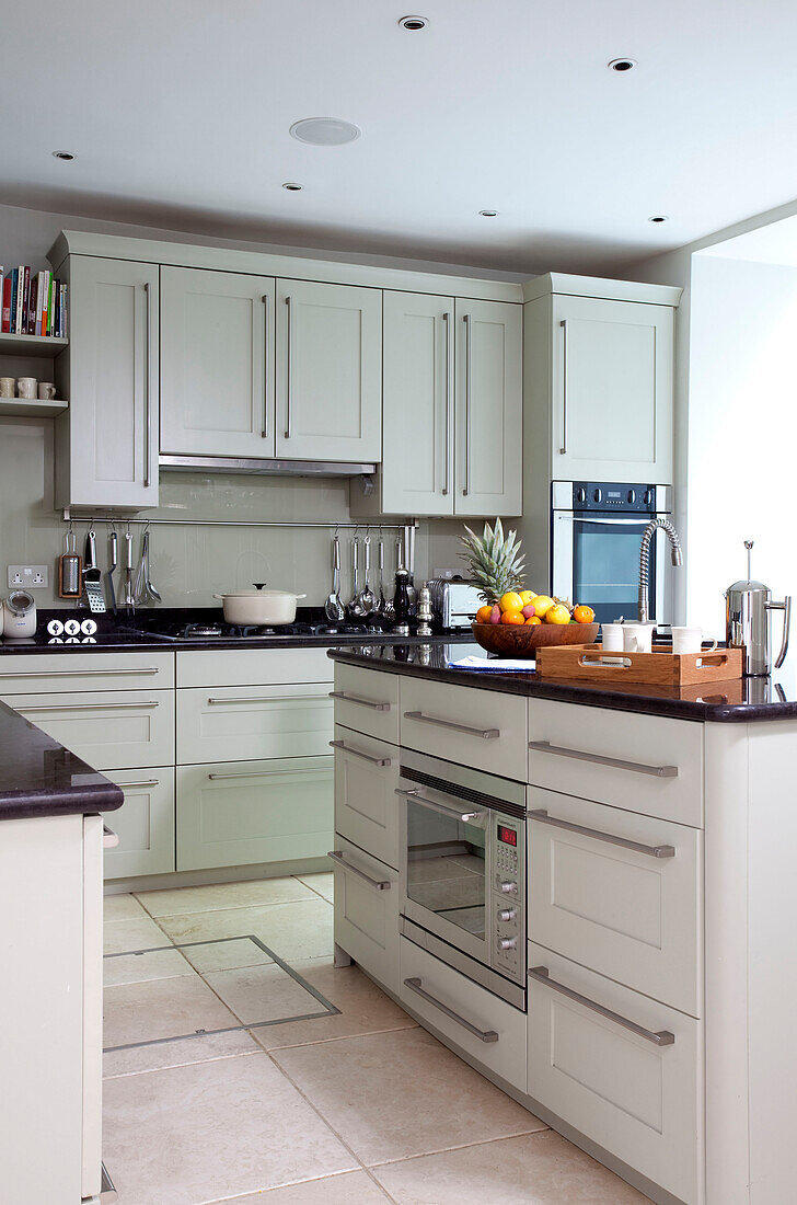 White fitted kitchen units and hob with utensil rack in contemporary London townhouse, UK