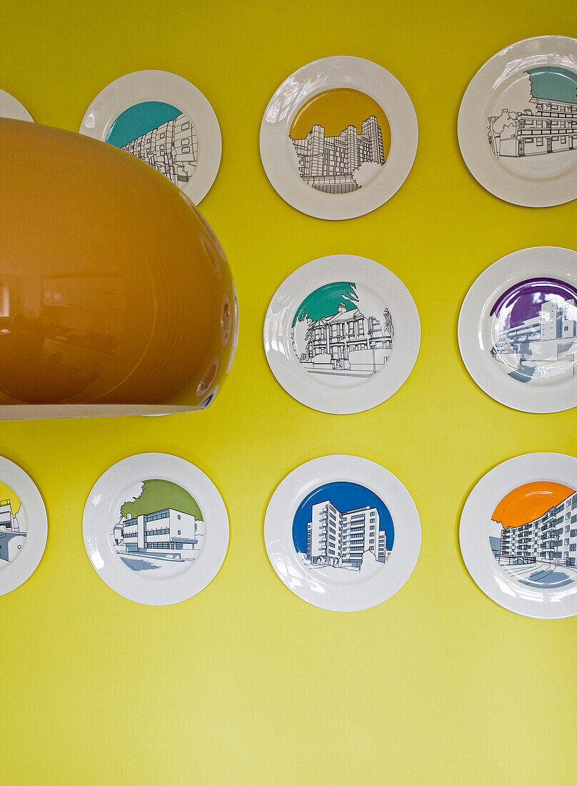 An der Wand montierte illustrative Teller und gelbe Pendellampe London UK