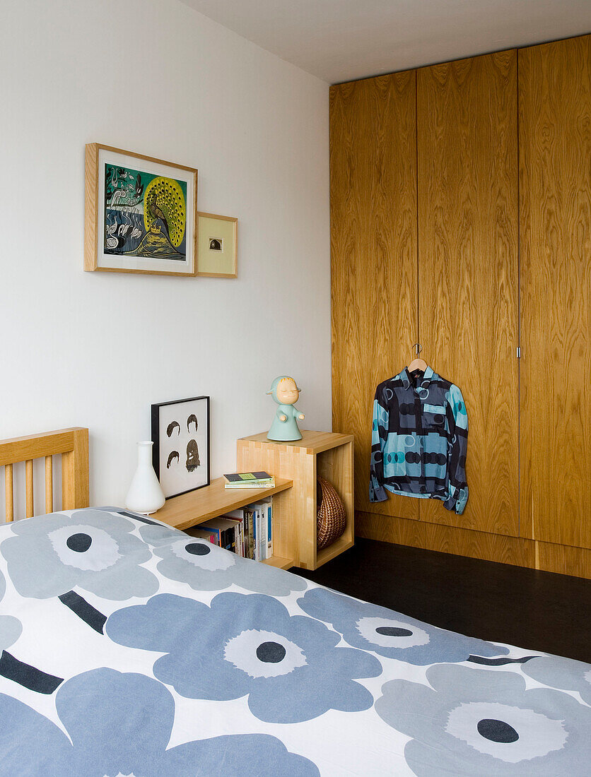 Bettdecke mit Blumenmuster und Kleiderschrank aus Holz in einem Haus in London, UK