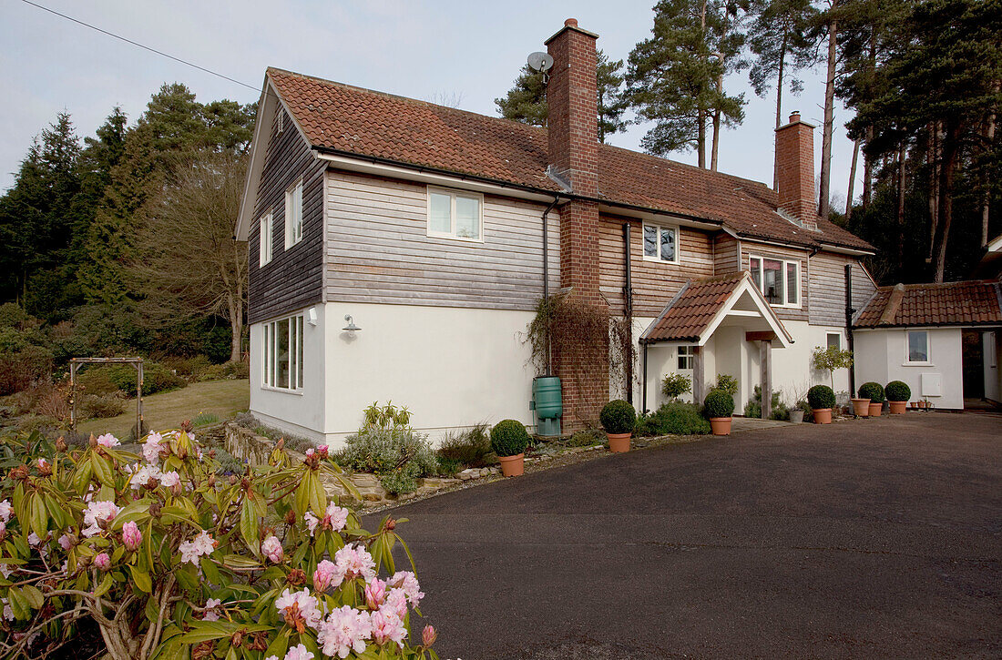 Driveway of wood panelled Sussex home with brick chimney UK