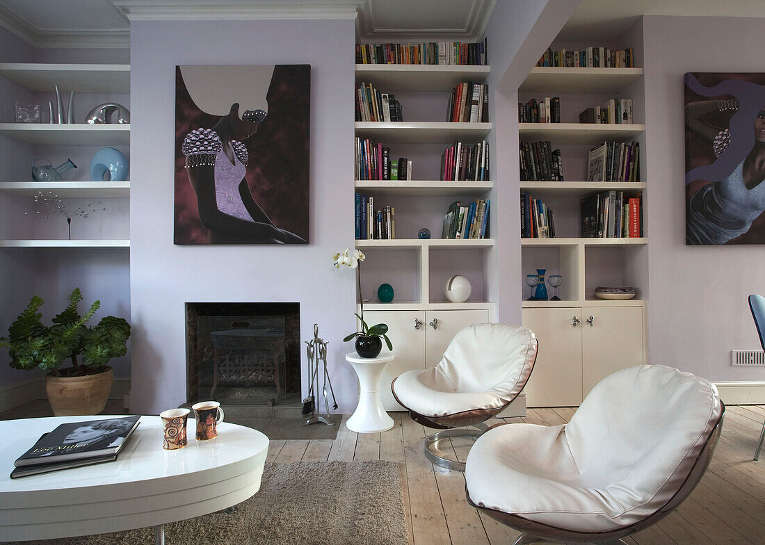 White leather vintage chairs in living room with recessed book shelves East Sussex home, England, UK