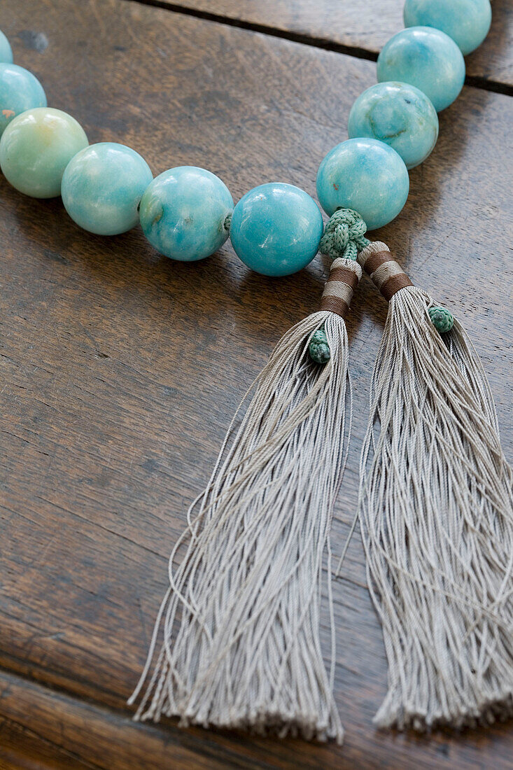Türkisfarbene Perlen und Quasten auf einer Holzoberfläche