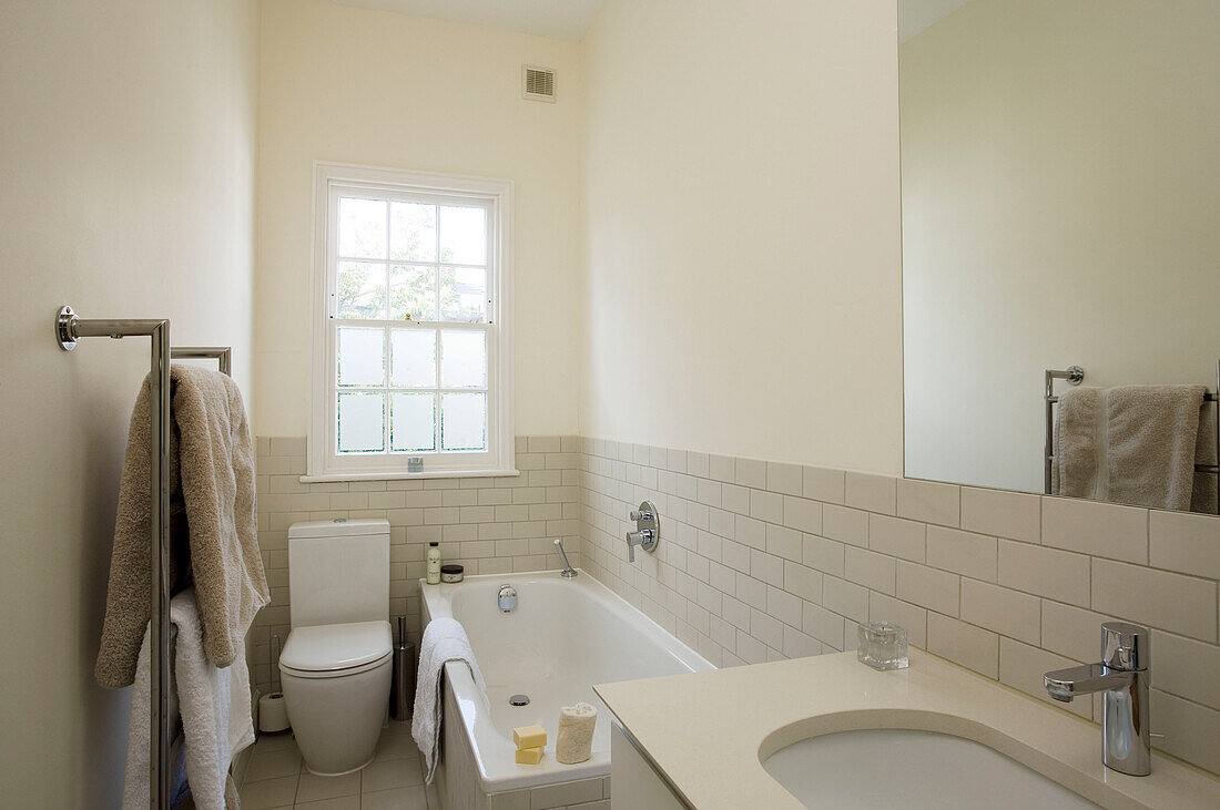 Frosted glass sash window in cream tiled bathroom