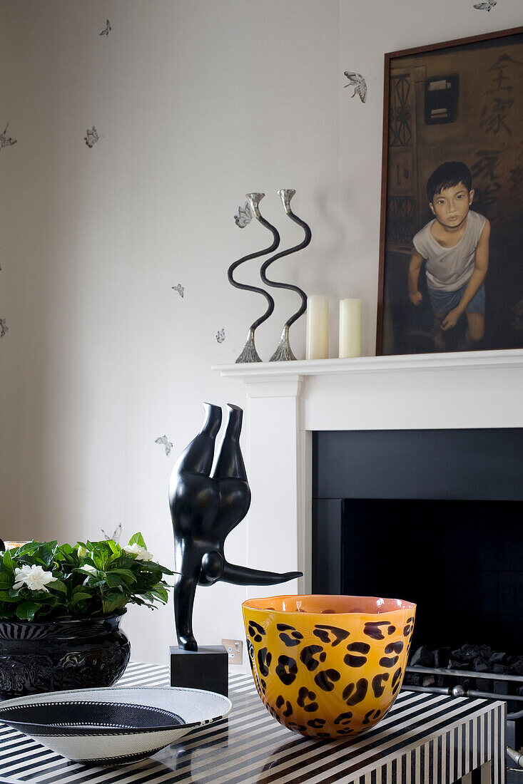 Homeware ornaments and statue with painting above fireplace in dining room in contemporary London townhouse, England, UK