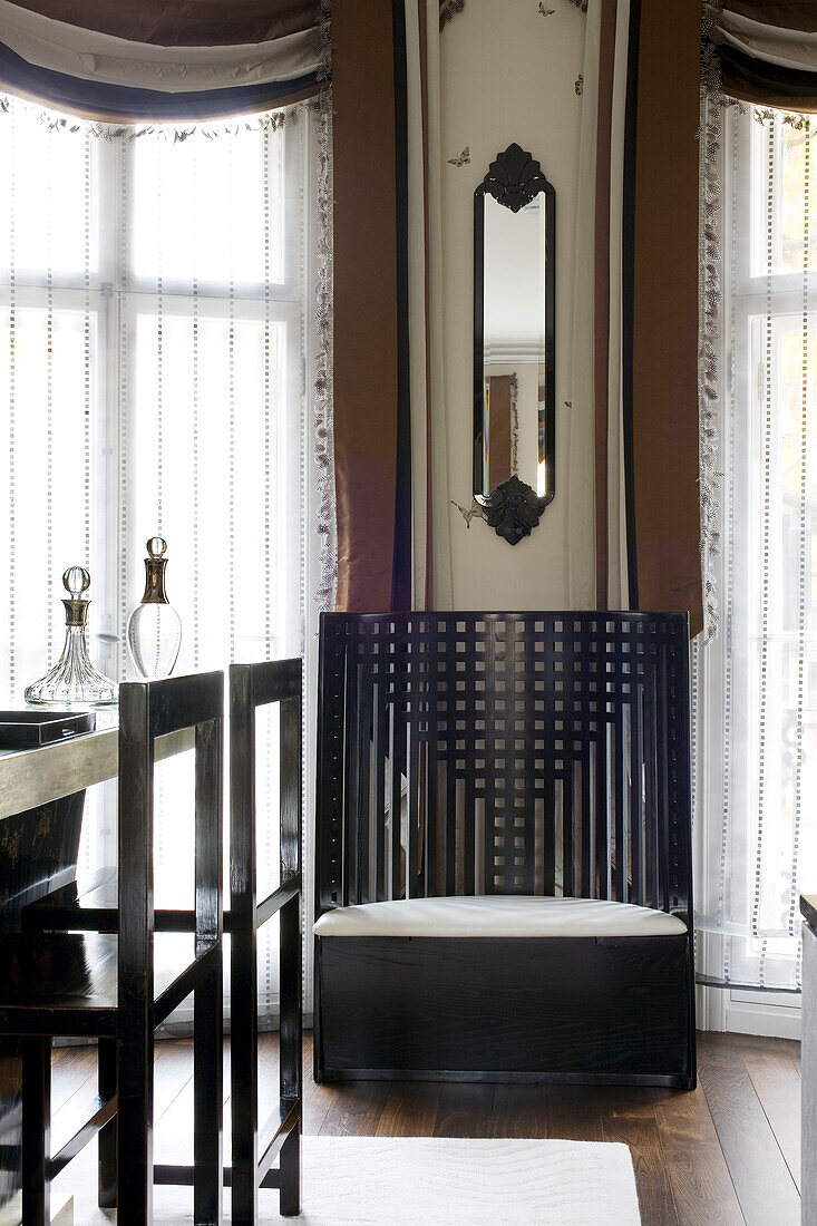 Schmaler Spiegel über vergittertem Holzstuhl im Esszimmer eines modernen Londoner Stadthauses, England, UK