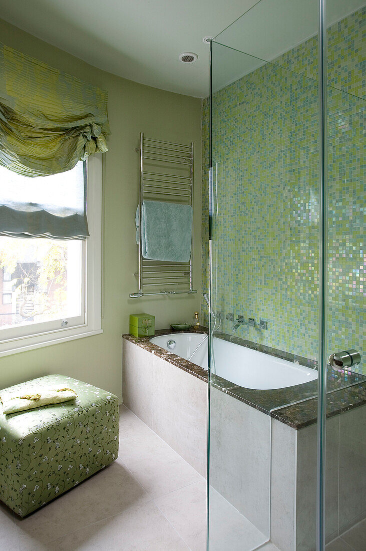 Pastel green tiled bathroom with fabric at window of contemporary London townhouse, England, UK