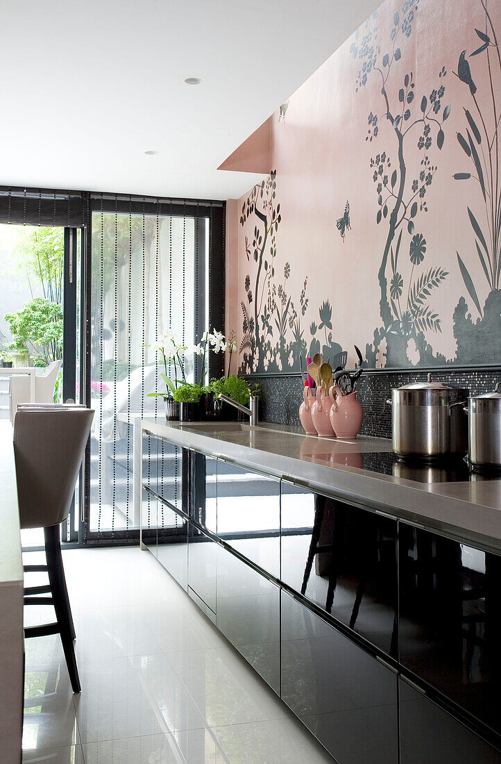 Saucepans on hob in black fitted kitchen with wall decor in contemporary London townhouse, England, UK