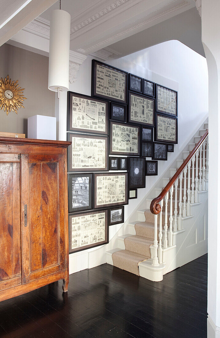 Antiker Holzschrank mit Architekturdrucken im Treppenhaus eines modernen Hauses, Hove, East Sussex, England, UK