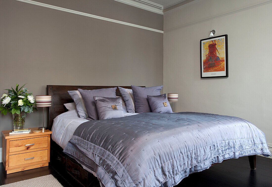 Fliederfarbene Bettbezüge in einem taubengrauen Schlafzimmer, modernes Haus, Hove, East Sussex, England, UK