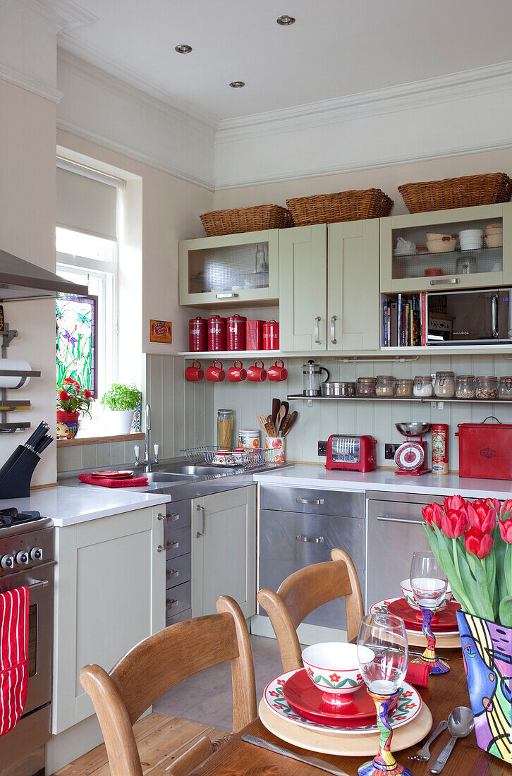 Edelstahl-Einbauschränke in Küche mit geschnittenen Tulpen auf Tisch in Londoner Stadthaus, England, UK