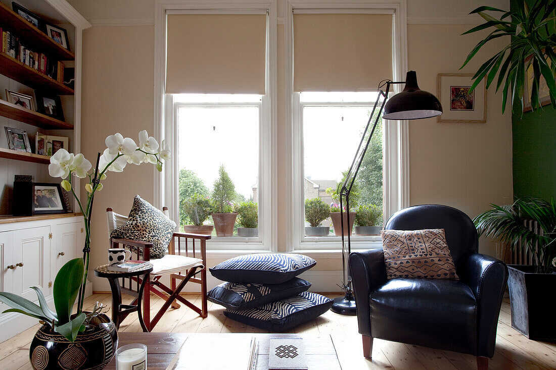 Schwarzer Ledersessel und übergroße anglepoise Stehlampe im Wohnzimmer mit Sprossenfenstern in einem Londoner Stadthaus, England, UK