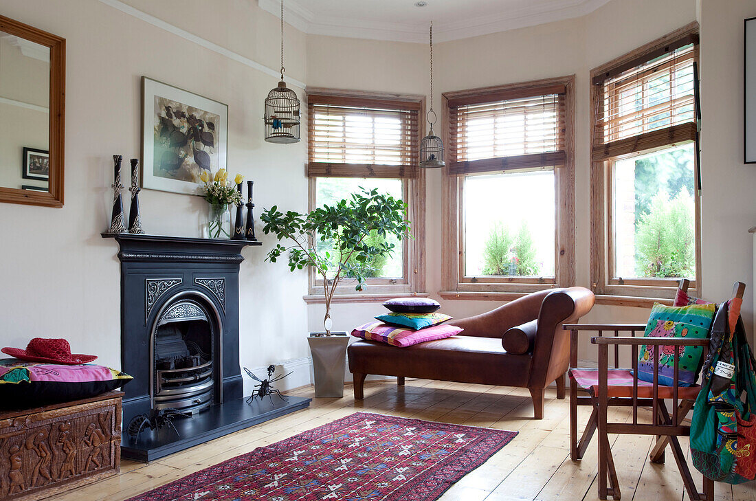 Chaiselongue aus braunem Leder im Erker des Wohnzimmers mit originalem Kamin in einem Londoner Stadthaus, England, Vereinigtes Königreich