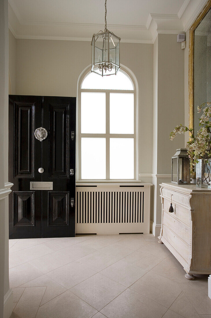 Open front door to entrance hallway with arched window in London townhouse