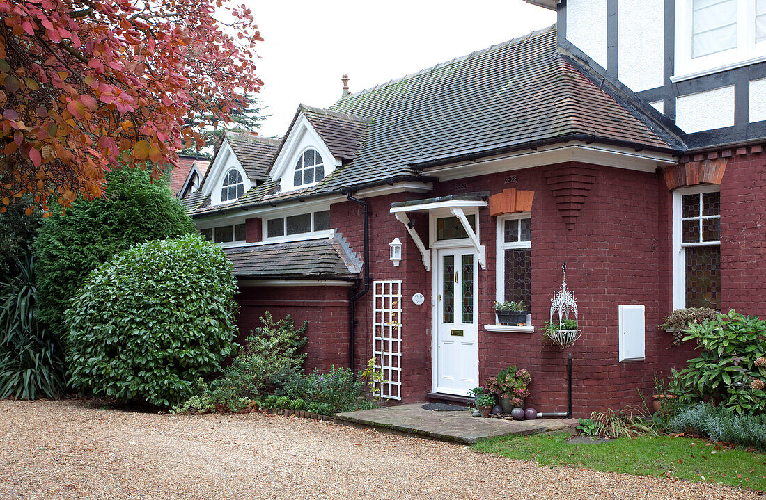 Schotterauffahrt und weiße Haustür vor rotem Backsteinhaus Surrey, England, Vereinigtes Königreich