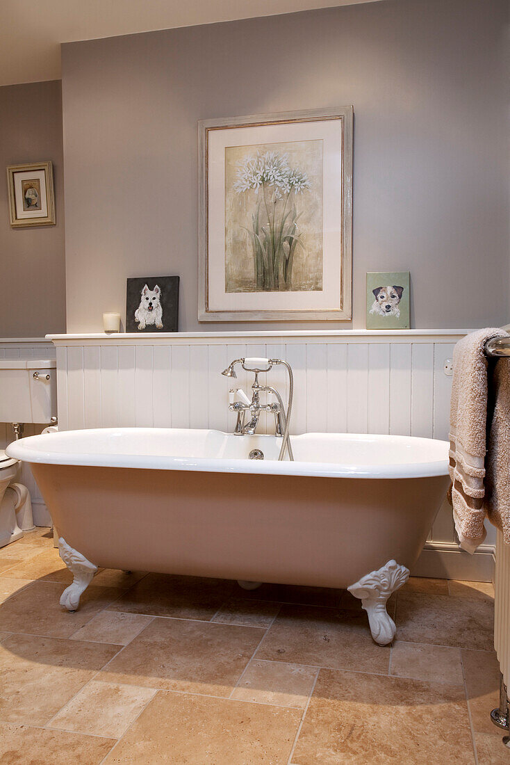 Freestanding rolltop bath and artwork in bathroom of Surrey home, England, UK