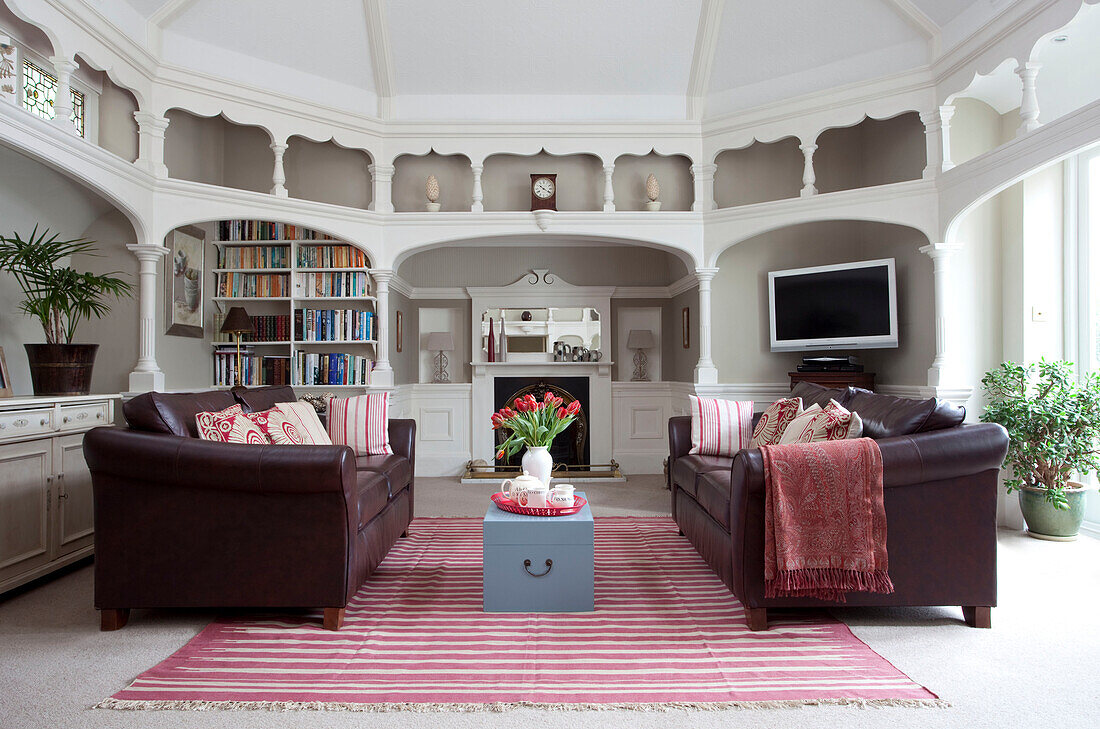 Braune Ledersofas in einem architektonisch gestalteten Wohnzimmer in einem Haus in Surrey, England, UK