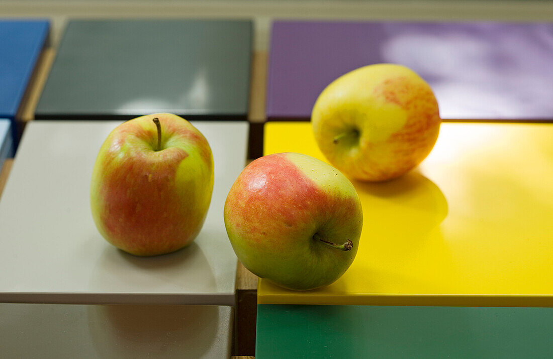Three apples on multicoloured tiles in London home, England, UK