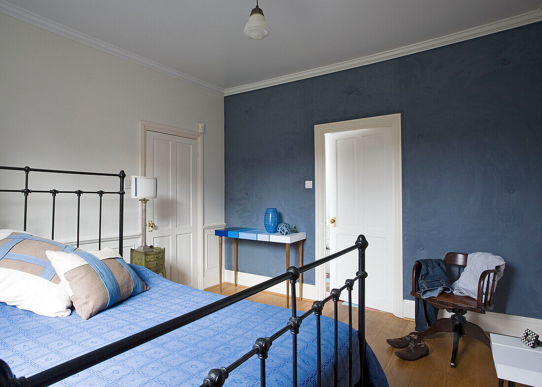 Menswear on chair in blue bedroom with metal bedframe in London home, England, UK