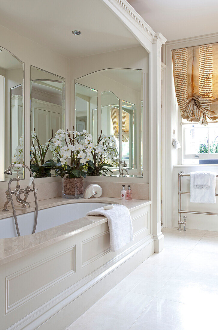 Nischenbadewanne mit Spiegeln und Orchidee in einem modernen Londoner Stadthaus, England, UK