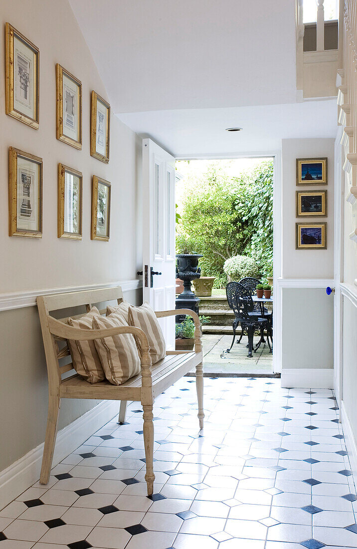 Open back door from tiled hallway with art display and bench seat in classic Tyne & Wear home, England, UK