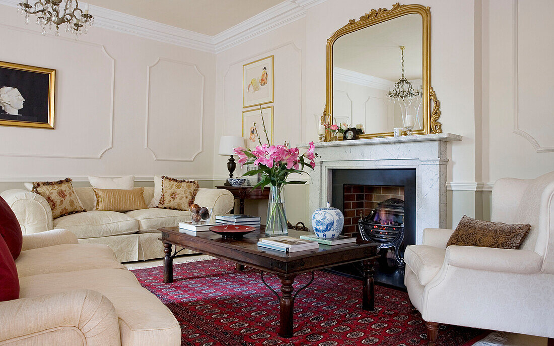 Weiße Sofas im Wohnzimmer mit gemustertem Teppich und vergoldetem Spiegel auf dem Kaminsims in einem klassischen Haus in Tyne & Wear, England, UK