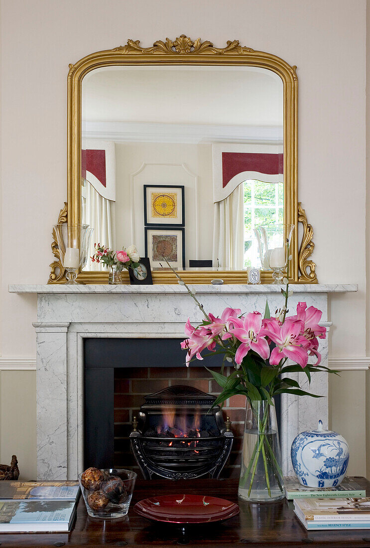 Geschnittene Lilien auf dem Couchtisch mit vergoldetem Spiegel auf dem Kaminsims in einem klassischen Haus in Tyne & Wear, England, Vereinigtes Königreich