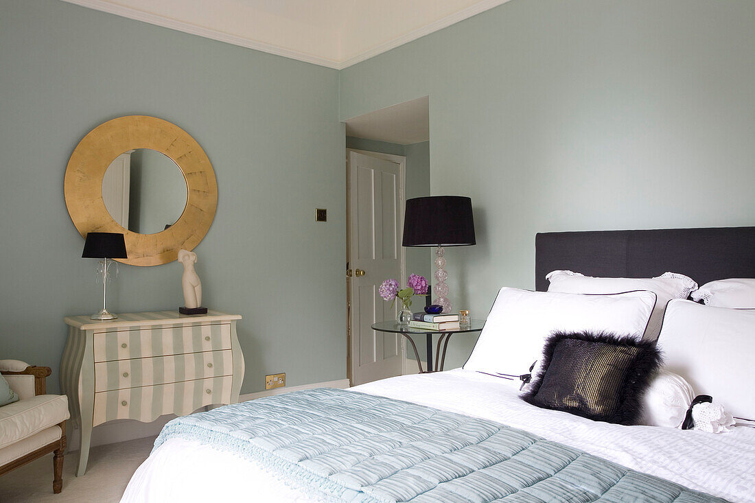 Hellblaues Schlafzimmer mit Straußenfederkissen und kreisförmigem Spiegel in einem klassischen Haus in Tyne & Wear, England, Vereinigtes Königreich