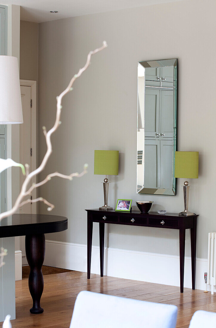 Rectangular mirror and matching lamps with wooden console in classic London home, UK