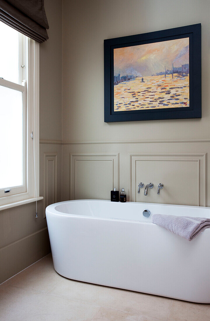 Contemporary white ceramic bath wt sash window in panelled bathroom of classic London home, UK