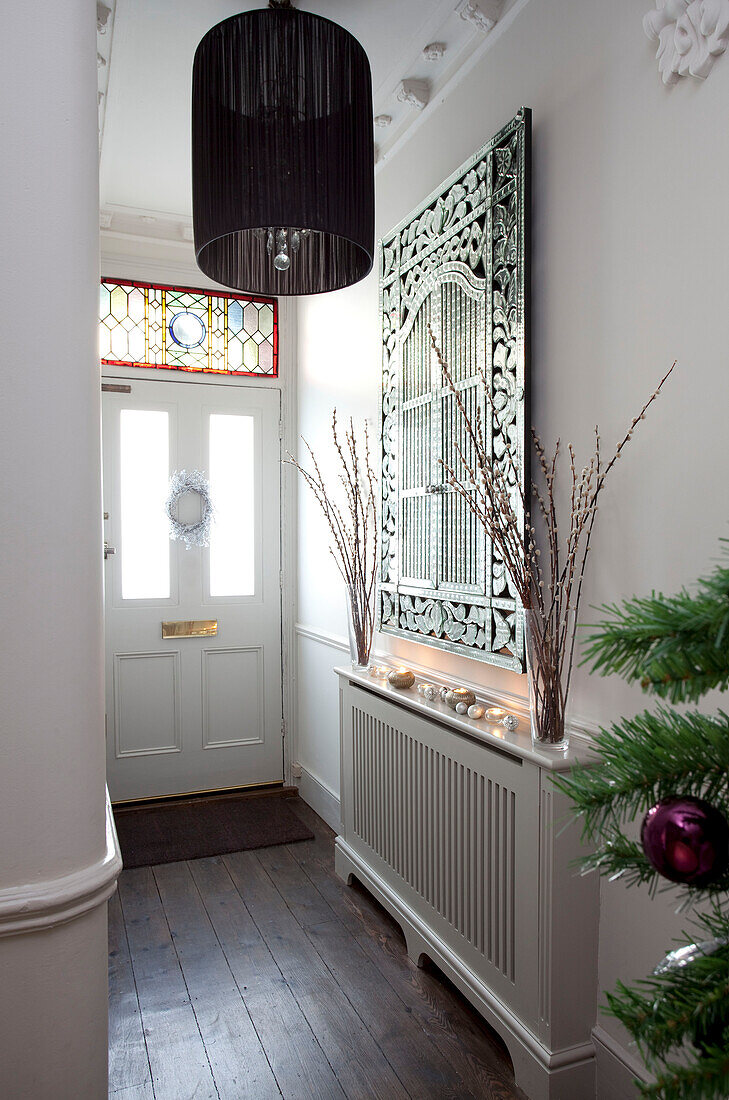 Decorative mirror above radiator in contemporary hallway of London home, UK