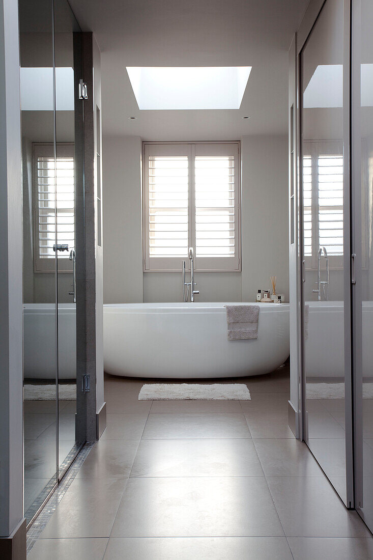White freestanding bath in tiled bathroom of contemporary London home, UK