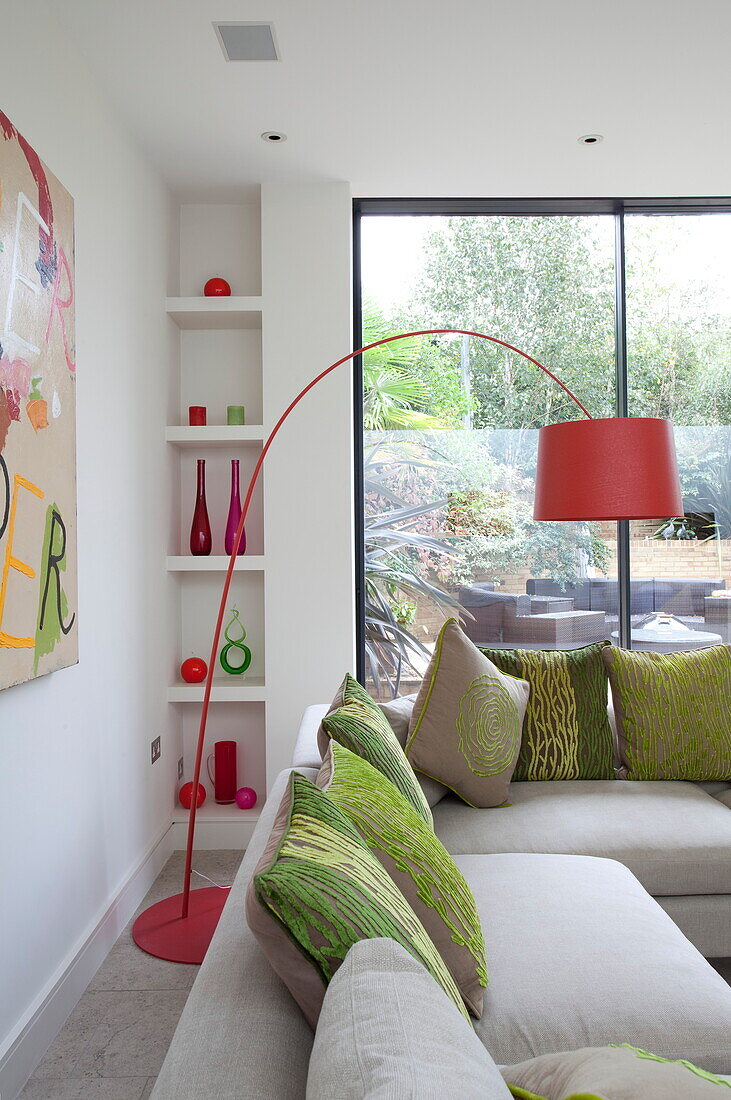 Rote Bogenlampe mit eingebautem Regal im Wohnzimmer eines modernen Hauses in London, England, UK