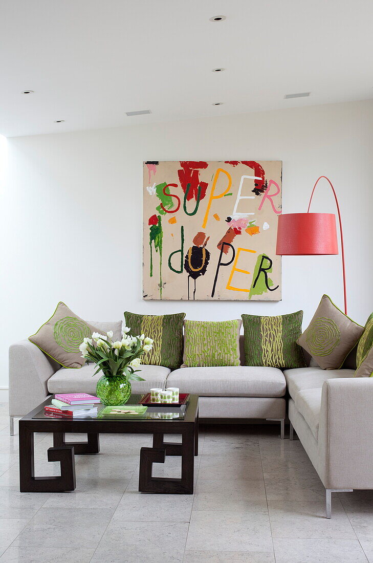 Artwork canvas with red arc lamp and corner sofa in living room of contemporary London home, England, UK