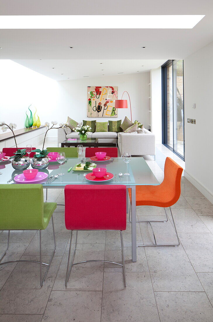 Mehrfarbige Esszimmerstühle am Tisch in einem offenen, modernen Haus in London, England, UK