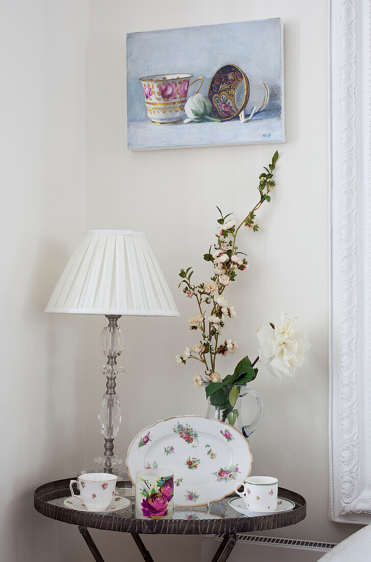 Chinaware and art canvas above side table with cut flowers in London home, UK