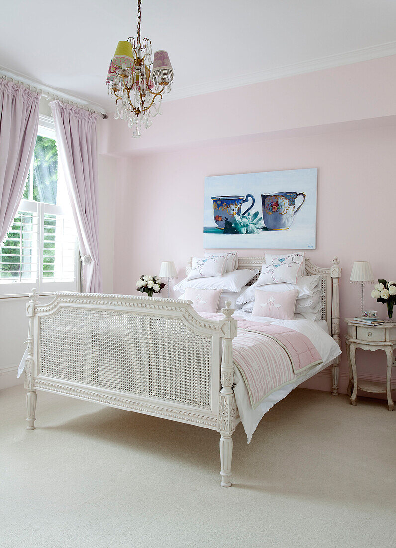 Kunstwerk aus Porzellan über einem weiß gestrichenen Doppelbett in einem pastellrosa Schlafzimmer in einem modernen Haus in London, Vereinigtes Königreich