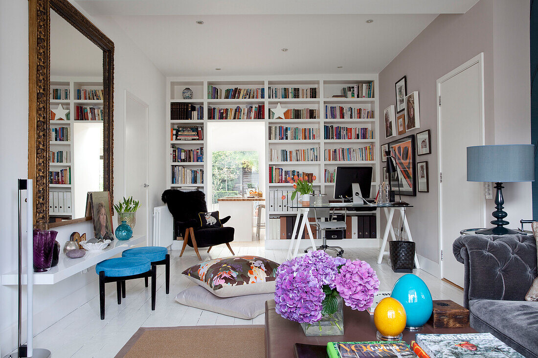 Bücherregale und Home Office in einer Ecke eines modernen Wohnzimmers mit großem Spiegel in einem Londoner Haus, UK