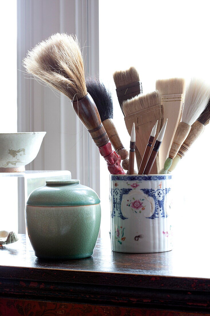 Calligraphy brushes with ornamental vase on sideboard in London home England UK