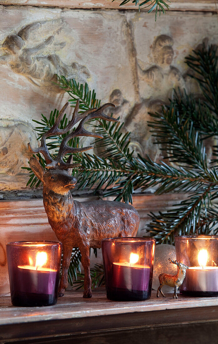 Reindeer statue and lit tealights on mantlepiece in London home, England, UK