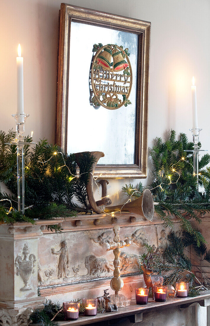 Gilt framed mirror above stone carved fireplace with pine tree decoration in London home, England, UK