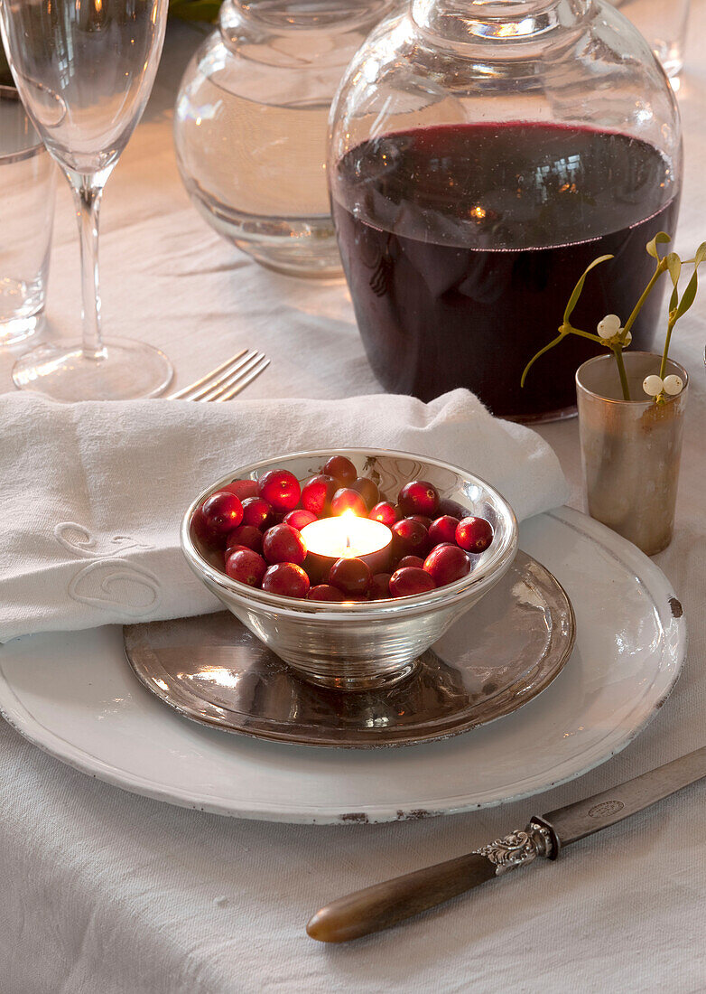 Lit tealight in bowl of berries on Christmas dinner table, London home, England, UK