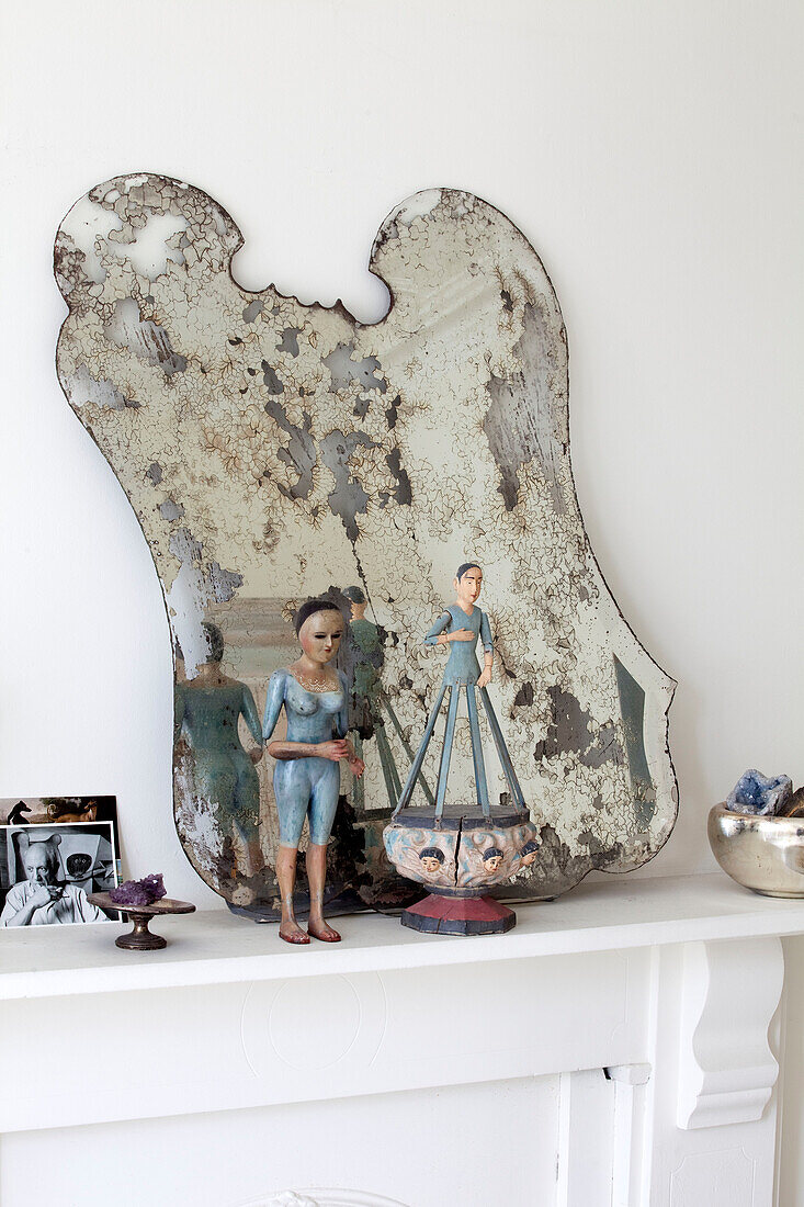 Figurines and distressed mirror on mantlepiece in London townhouse, England, UK