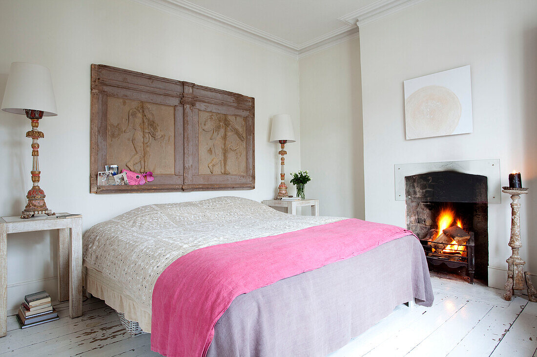 Lit fire in bedroom with architectural salvage in London townhouse, England, UK