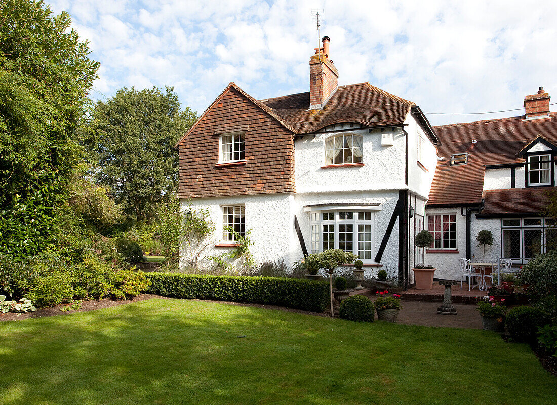 Mit Rasen bepflanztes Äußeres eines Bauernhauses mit weißem Kieselstein und Dachbalken in Sussex, England, Vereinigtes Königreich