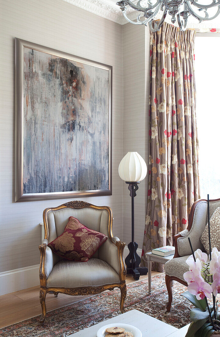 Artwork above gilt vintage chair in living room of London home, UK